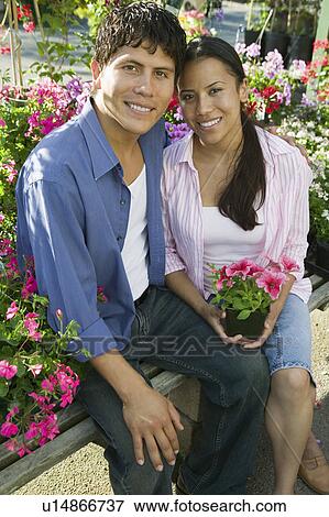 Couple Sitting Among flowers at plant nursery, portrait View Large Photo Image Stock Photo - Couple Sitting Among flowers at plant nursery, portrait. Fotosearch