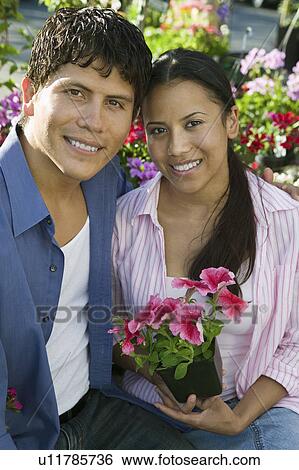 Couple Sitting Among flowers at plant nursery, portrait View Large Photo Image Stock Photograph - Couple Sitting Among flowers at plant nursery, portrait. Fotosearch