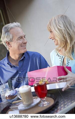Couple sitting at cafe table on Shopping Trip, wife opening gift View Large Photo Image Stock Image - Couple sitting at cafe table on Shopping Trip, wife opening gift. Fotosearch