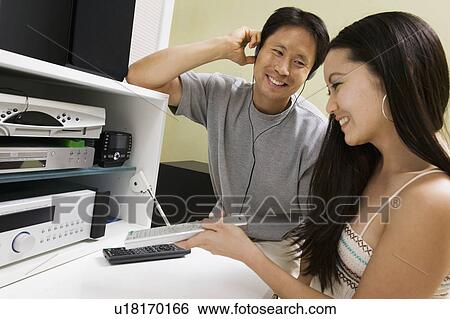 Couple sitting next to Home Theatre System, man listening on headphones, close up View Large Photo Image Stock Photograph - Couple sitting next to Home Theatre System, man listening on headphones, close up. Fotosearch