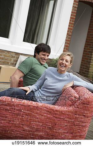 Couple sitting on sofa outside house View Large Photo Image Stock Photograph - Couple sitting on sofa outside house. Fotosearch