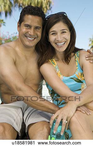 Stock Image - Couple sitting outdoors, portrait.. Fotosearch