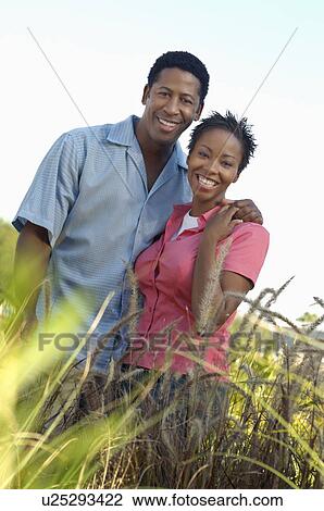 Couple smiling in grass meadow, (portrait) View Large Photo Image Stock Image - Couple smiling in grass meadow, (portrait). Fotosearch