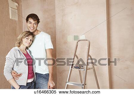 Stock Photography - Couple standing, embracing in unrenovated room, portrait. Fotosearch