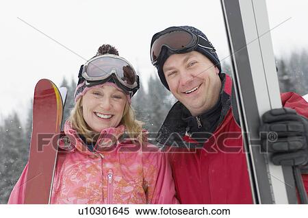 Couple standing outdoors with skis, half length View Large Photo Image Stock Photography - Couple standing outdoors with skis, half length. Fotosearch