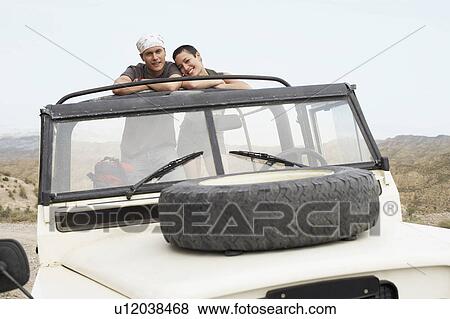 Couple standing side by side in stationary four wheel drive car in desert, portrait View Large Photo Image Stock Photo - Couple standing side by side in stationary four wheel drive car in desert, portrait. Fotosearch