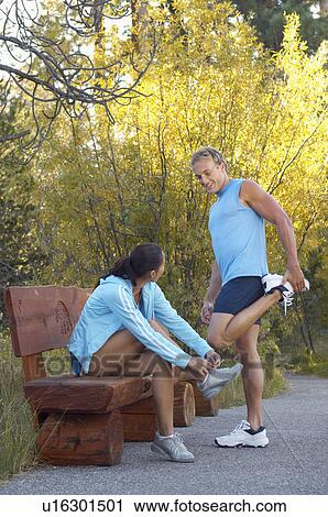 Stock Image - Couple stretching before run through woodland. Fotosearch