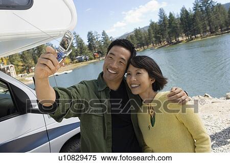 Couple taking picture of selves outside RV at lake View Large Photo Image Stock Photography - Couple taking picture of selves outside RV at lake. Fotosearch