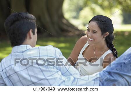 Stock Photo - Couple talking, lying on park lawn. Fotosearch