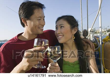 Stock Image - Couple toasting with white wine on boat. Fotosearch