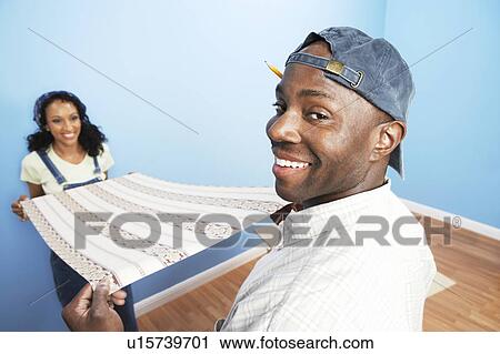 Couple unrolling wallpaper in room, back view View Large Photo Image Stock Image - Couple unrolling wallpaper in room, back view. Fotosearch