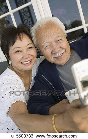 Stock Image - Couple using mobile phone, outdoors. Fotosearch