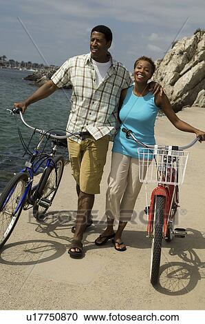 Couple walking with bicycles at beach View Large Photo Image Stock Image - Couple walking with bicycles at beach. Fotosearch