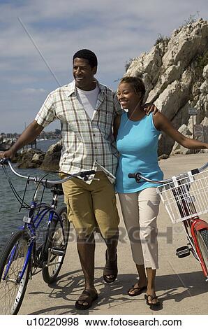 Couple walking with bicycles at beach View Large Photo Image Stock Photo - Couple walking with bicycles at beach. Fotosearch
