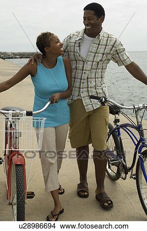 Couple walking with bicycles on beach View Large Photo Image Picture - Couple walking with bicycles on beach. Fotosearch