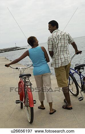 Couple walking with bicycles on beach View Large Photo Image Stock Photo - Couple walking with bicycles on beach. Fotosearch