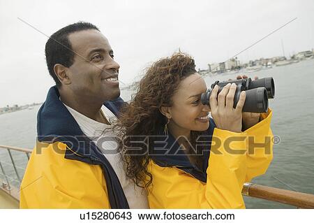 Couple wearing yellow anoraks on yacht, woman looking through binoculars View Large Photo Image Stock Image - Couple wearing yellow anoraks on yacht, woman looking through binoculars. Fotosearch