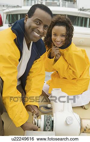Couple wearing yellow anoraks on yacht, (portrait) View Large Photo Image Stock Photograph - Couple wearing yellow anoraks on yacht, (portrait). Fotosearch
