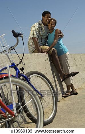 Couple with bicycles, embracing on wall View Large Photo Image Stock Image - Couple with bicycles, embracing on wall. Fotosearch