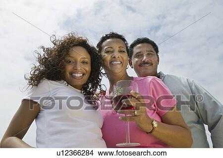 Couple with friend outdoors, (portrait), (low angle view) View Large Photo Image Picture - Couple with friend outdoors, (portrait), (low angle view). Fotosearch