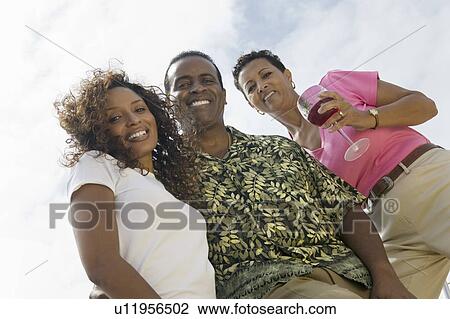 Couple with friend outdoors, (portrait), (low angle view) View Large Photo Image Stock Image - Couple with friend outdoors, (portrait), (low angle view). Fotosearch
