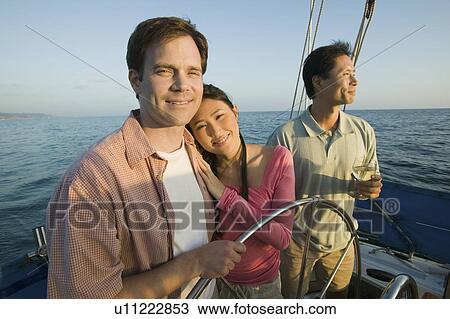 Couple with friend relaxing on yacht, (portrait) View Large Photo Image Stock Image - Couple with friend relaxing on yacht, (portrait). Fotosearch