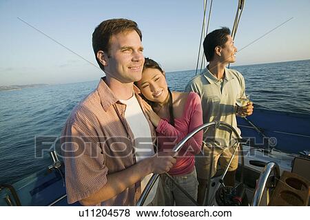 Stock Photo - Couple with friend relaxing on yacht. Fotosearch