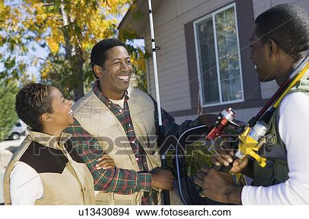 Picture - Couple with male friend preparing to fishing trip, smiling. Fotosearch