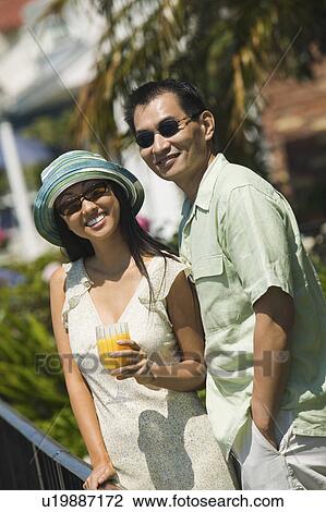 Stock Image - Couple with orange juice, outdoors, (portrait). Fotosearch