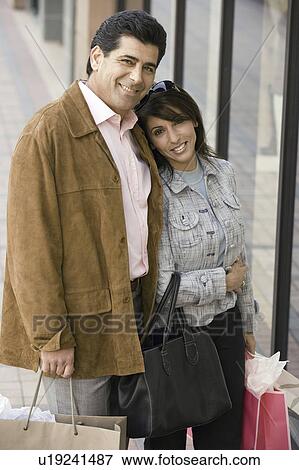 Stock Photo - Couple with shopping bags, portrait. Fotosearch