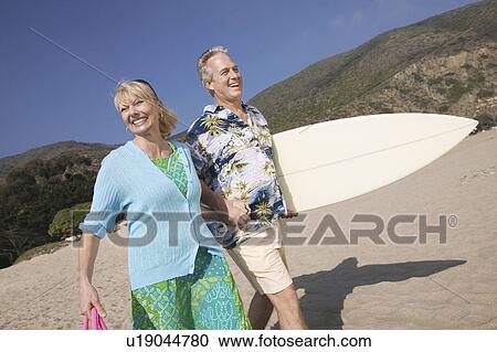 Couple with surfboard, smiling on beach View Large Photo Image Stock Image - Couple with surfboard, smiling on beach. Fotosearch