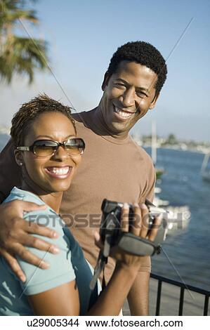 Picture - Couple with video camera at marina, (portrait). Fotosearch
