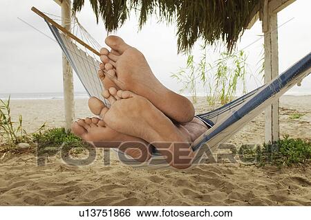 Stock Photograph - Couple's Feet on Edge of Hammock on Beach. Fotosearch