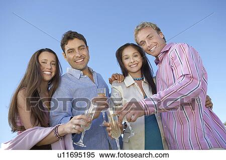Couples toasting, Celebrating with Champagne outdoors, low angle view View Large Photo Image Stock Photography - Couples toasting, Celebrating with Champagne outdoors, low angle view. Fotosearch