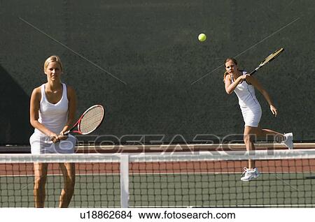 Picture - Doubles Player Hitting tennis ball with Forehand, team-mate standing at net. Fotosearch