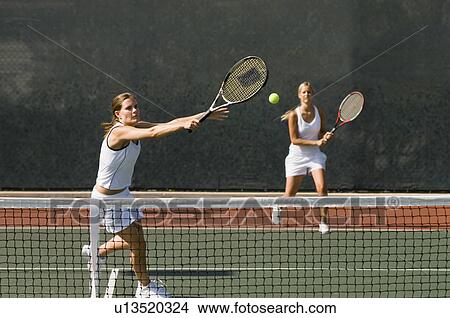 Picture - Doubles Player stretching, Hitting tennis ball with Backhand near net. Fotosearch