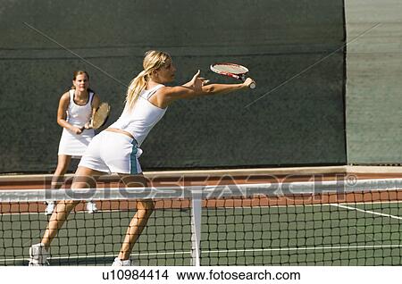 Doubles tennis Player stretching to hit tennis ball with Backhand View Large Photo Image Picture - Doubles tennis Player stretching to hit tennis ball with Backhand. Fotosearch
