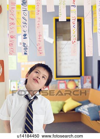 Elementary schoolboy looking up at paper strips with alphabet in classroom View Large Photo Image Stock Image - Elementary schoolboy looking up at paper strips with alphabet in classroom. Fotosearch