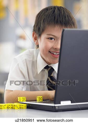 Elementary schoolboy using laptop sitting in classroom View Large Photo Image Stock Image - Elementary schoolboy using laptop sitting in classroom. Fotosearch