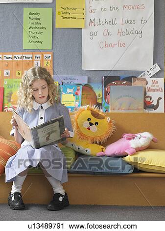 Elementary schoolgirl reading book on couch in classroom View Large Photo Image Stock Image - Elementary schoolgirl reading book on couch in classroom. Fotosearch