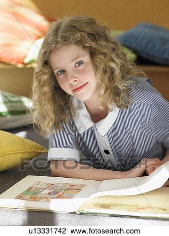 Elementary schoolgirl reading book lying on floor, portrait View Large Photo Image Stock Image - Elementary schoolgirl reading book lying on floor, portrait. Fotosearch