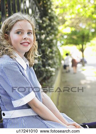 Elementary schoolgirl sitting against school fence View Large Photo Image Stock Image - Elementary schoolgirl sitting against school fence. Fotosearch