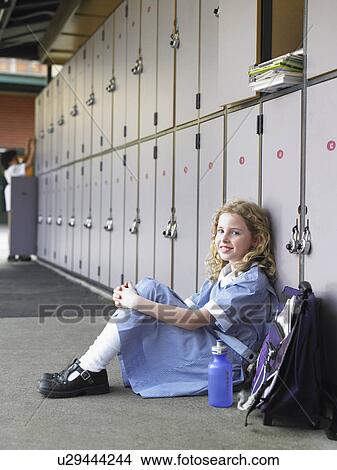 Elementary schoolgirl sitting on floor against school lockers, portrait View Large Photo Image Picture - Elementary schoolgirl sitting on floor against school lockers, portrait. Fotosearch