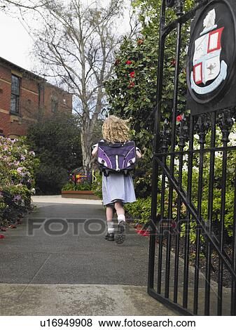 Elementary schoolgirl walking towards school building, back view View Large Photo Image Stock Photo - Elementary schoolgirl walking towards school building, back view. Fotosearch