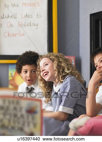 Stock Image - Elementary students laughing in classroom. Fotosearch