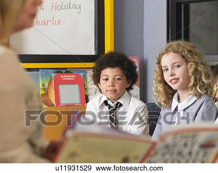 Elementary students listening to teacher read in classroom View Large Photo Image Stock Photo - Elementary students listening to teacher read in classroom. Fotosearch