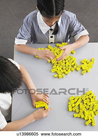 Stock Photography - Elementary students playing with dice on desk, elevated view. Fotosearch