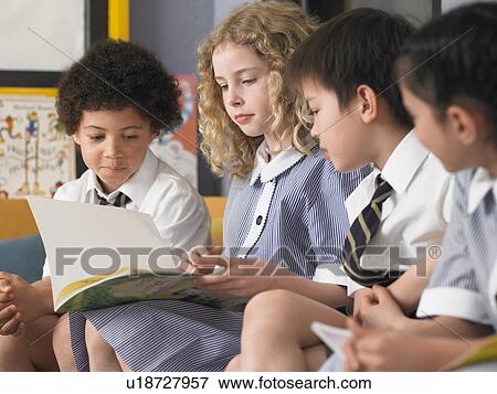 Stock Photo - Elementary students reading book, sitting in row in classroom. Fotosearch