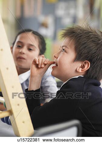 Stock Image - Elementary students sitting in classroom. Fotosearch