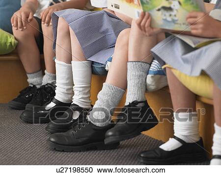 Stock Image - Elementary students sitting in row in classroom, low section. Fotosearch
